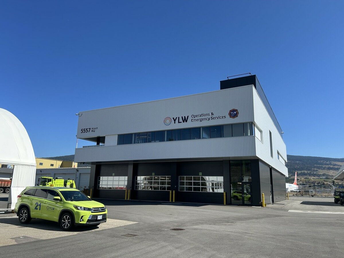 Exterior of the two-storey YLW Operations & Emergency Services Building at Kelowna International Airport, with an airport response vehicle parked in front.